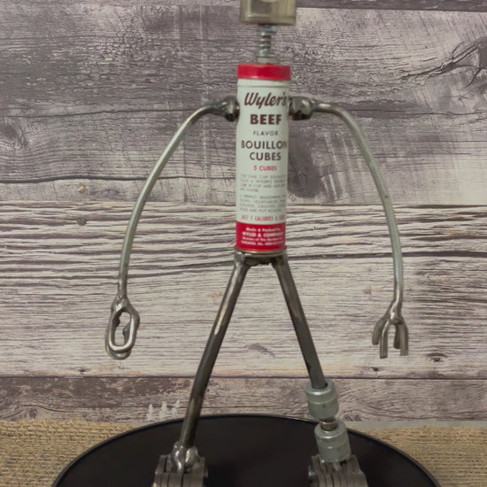 Meet Wyler!  This one-of-a-kind robot scrap art sculpture is made from a vintage beef bouillon cube tin body, vintage mini oiler head with uniquely reimagined scrap metal arms made from lamp parts and scrap metal legs. This bot would look great in a kitchen or in any room décor. 