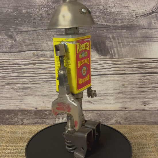Meet Keener! This one-of-a-kind robot scrap art sculpture is made from a vintage spice tin body, vintage oiler head with uniquely reimagined scrap metal arms and spark plug legs. This adorable little scrap bot is beaming with personality!  See video for a 360-degree view!  Features:   Height: 36 cm or 14 inches tall Width: approximately 10 cm or 4 inches wide Weight: .907 kg or 2 lbs